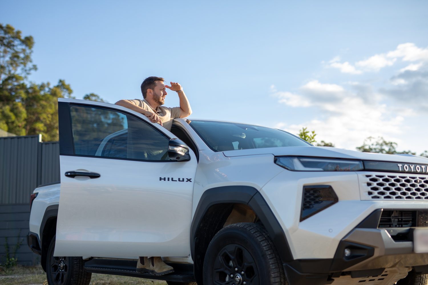 Ramon Palomar laughing on the phone in the doorway of his ute, parked at an estate